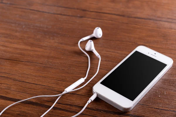 Białe cellphone rezygnować słuchawki na tle drewniane lakierowane — Zdjęcie stockowe