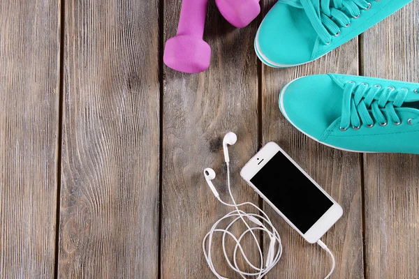 Białe cellphone rezygnować słuchawki i różowy głupie dzwonki i Półbuty gumowe na drewniane tła — Zdjęcie stockowe