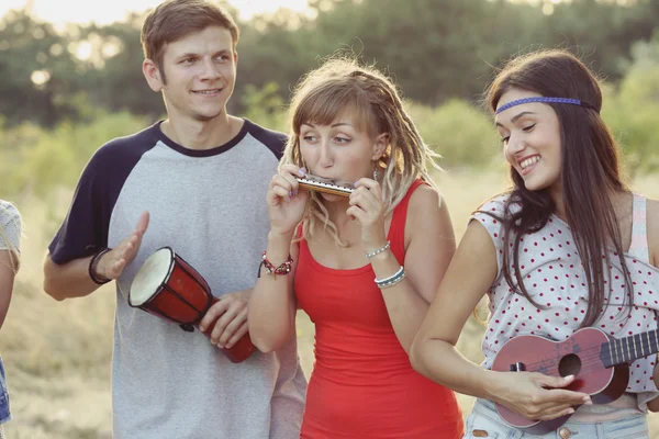 Happy smiling friends playing musical instruments in the forest outdoors