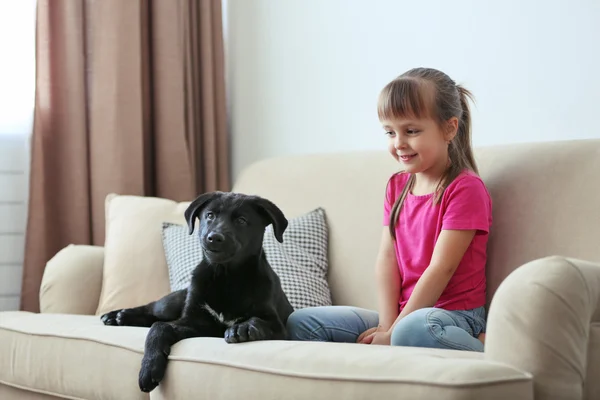 Bambina con cucciolo sul divano — Foto Stock