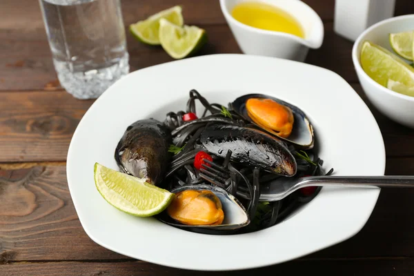 Cooked pasta, mussel and lime on brown wooden background — Stock Photo, Image