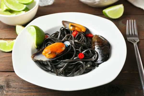 Cooked pasta, mussel and lime on brown wooden background — Stock Photo, Image