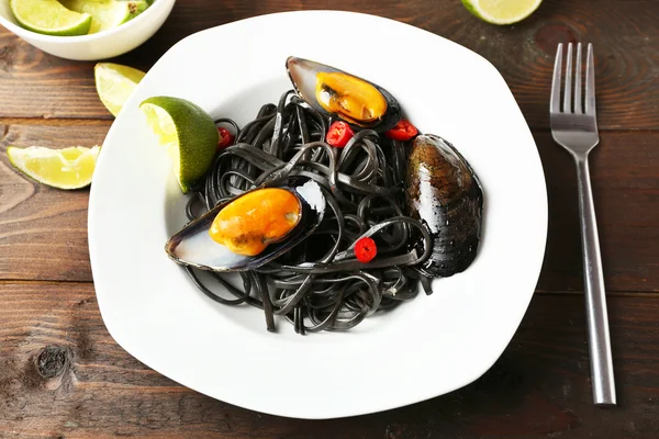 Cooked pasta, mussel and lime on brown wooden background — Stock Photo, Image