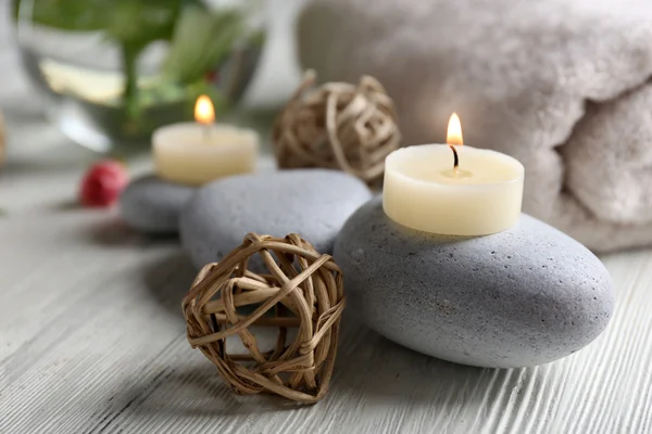 Composition of flowers, candles and stones on white wooden background, in spa salon — Stock Photo, Image