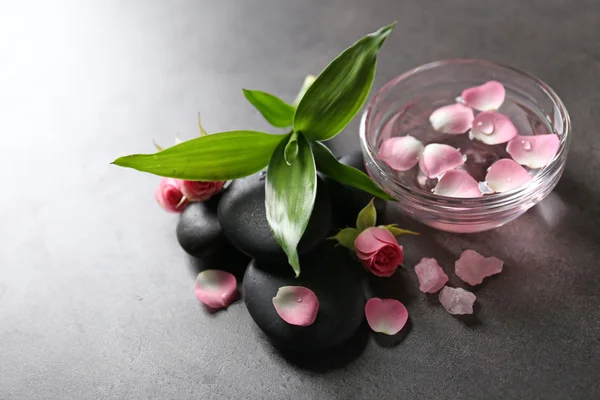 Wellness-Komposition aus Steinen, Blumen und Blütenblättern, auf grauem Hintergrund — Stockfoto