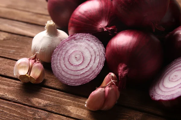 Cebollas rojas frescas con ajo sobre fondo de madera — Foto de Stock