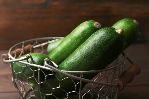 Fresh zucchini in wicker basket on wooden background — Stock Photo, Image