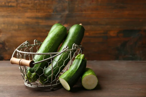 Fresh zucchini in wicker basket on wooden background — Stock Photo, Image