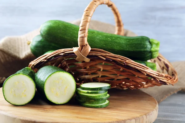 Zucchine fresche tagliate a fette sul tagliere, su fondo di legno — Foto Stock