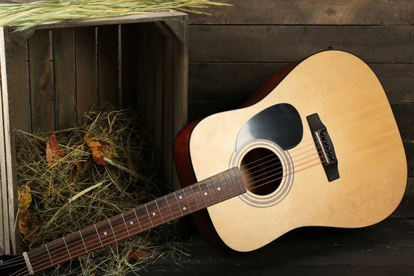 Akusztikus gitár, széna, a fa háttér doboz ellen — Stock Fotó