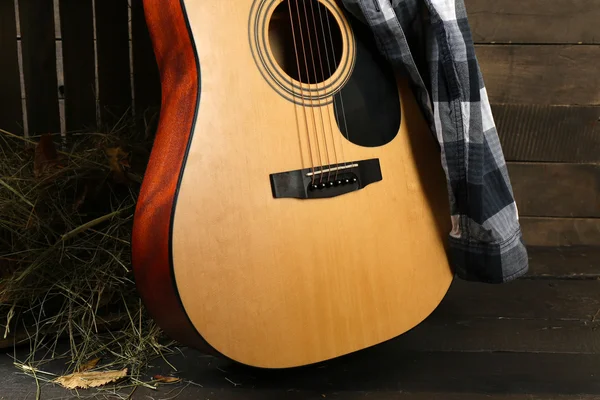 Guitarra acústica e camisa quadriculada azul contra caixa com feno em fundo de madeira, de perto — Fotografia de Stock