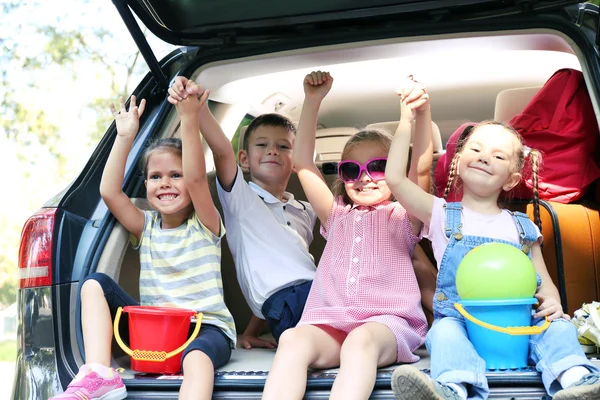 Meisjes en jongen zitten op de auto kofferbak — Stockfoto