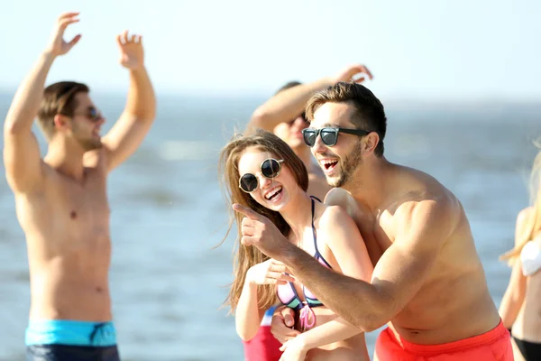 Happy couple and friends relaxing at beach — Stock Photo, Image