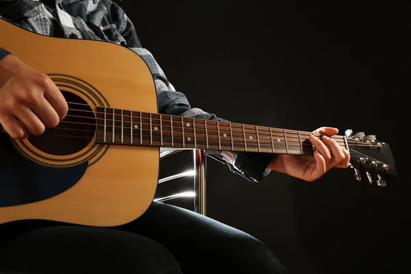 Музикант грає на гітарі на чорному фоні, крупним планом — стокове фото