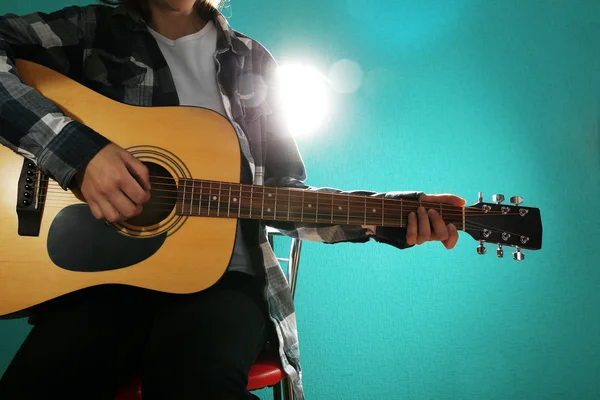 Músico toca la guitarra sobre fondo azul, de cerca — Foto de Stock