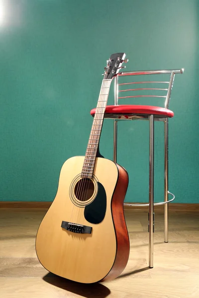 Guitar with bar stool on the floor against blue background in the studio — Stock Photo, Image