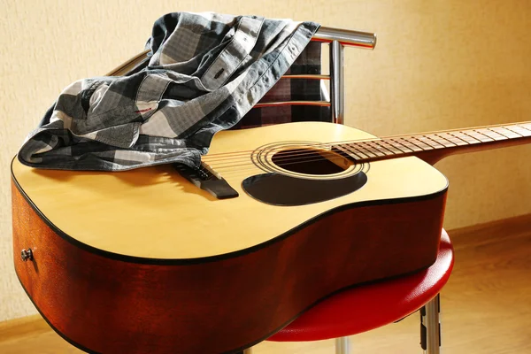Akustisk guitar på rød taburet i studiet, nærbillede - Stock-foto