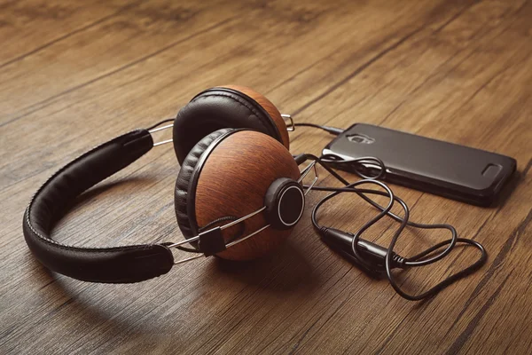 Ακουστικά και smartphone για καφέ φόντο ξύλινη — Φωτογραφία Αρχείου