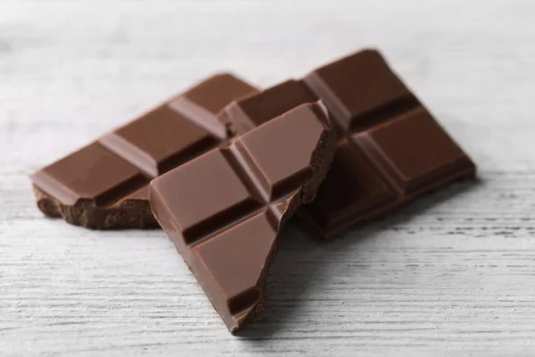 Pedaços de chocolate preto na cor de fundo de madeira — Fotografia de Stock