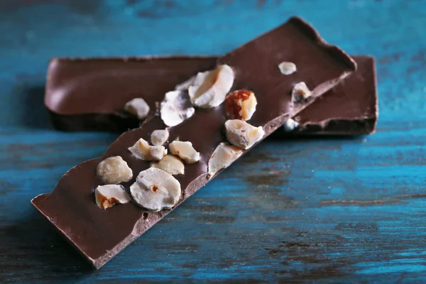 Fındık rengi ahşap arka plan üzerinde siyah çikolata parçaları — Stok fotoğraf