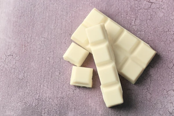 Pedaços de chocolate branco na cor de fundo de madeira — Fotografia de Stock