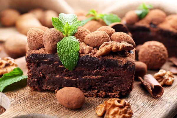 Un morceau de gâteau au chocolat avec noix et menthe sur la table, gros plan — Photo