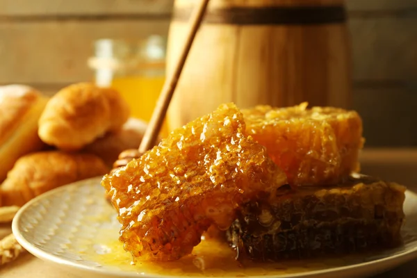 Panales en plato, panecillos calientes en cesta sobre fondo de madera —  Fotos de Stock