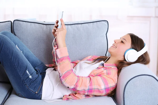 Linda chica escuchando música en el sofá —  Fotos de Stock