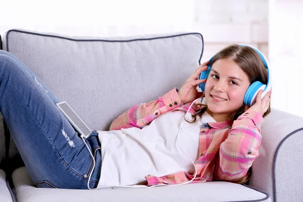 Menina bonita ouvindo música no sofá — Fotografia de Stock