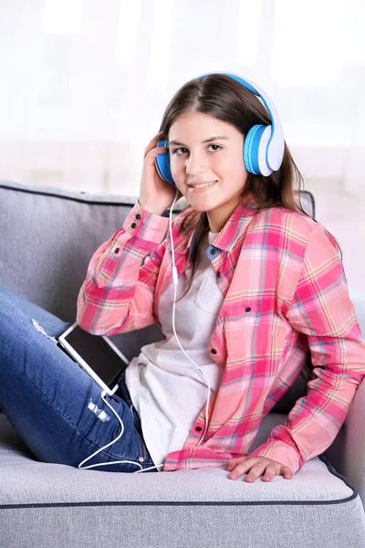 Menina bonita ouvindo música no sofá — Fotografia de Stock