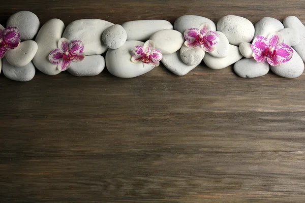 Spa stones and orchid on wooden background — Stock Photo, Image