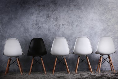 Gri arka plan üzerinde beyaz ve siyah sandalye ile şık anlayışı