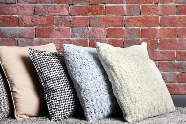 Almohadas multicolores en la pared de ladrillo —  Fotos de Stock