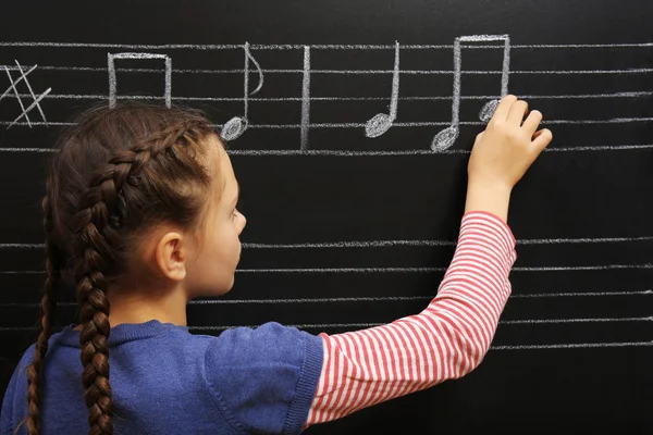 Chica escribiendo notas musicales — Foto de Stock