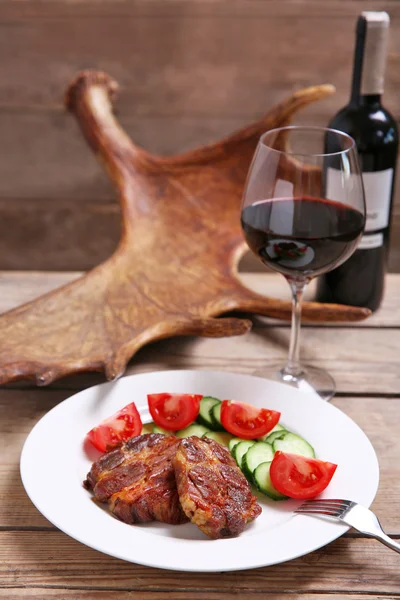 Filete de venado asado y verduras frescas en plato, sobre fondo de madera — Foto de Stock