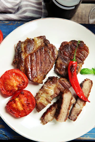 Filet de bœuf rôti et légumes grillés sur assiette, sur fond bois — Photo