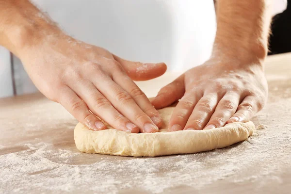 Manos amasando masa para pizza en la mesa de madera, primer plano — Foto de Stock