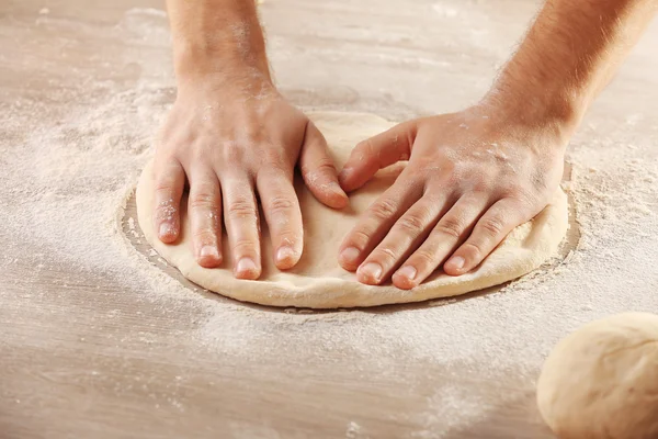 Manos preparando base de masa para pizza en la mesa de madera, primer plano — Foto de Stock