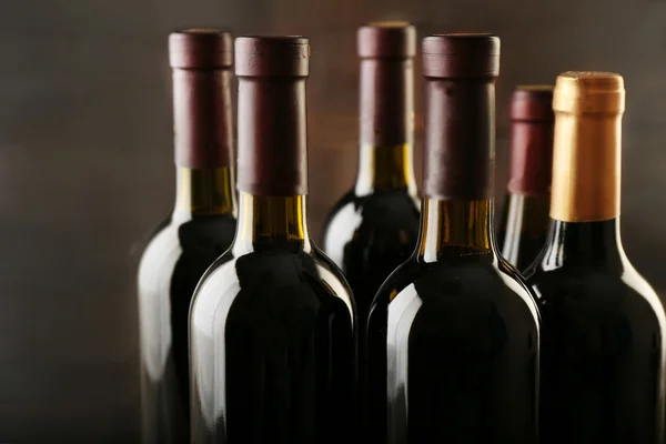 Butelki z winem na drewnianym tle, zbliżenie — Zdjęcie stockowe