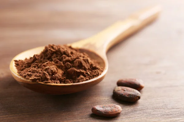 Cucchiaio di legno con cacao in polvere sul tavolo, primo piano — Foto Stock