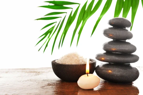 Spa stones with candle, green leaves and sea salt, isolated on white — Stock Photo, Image