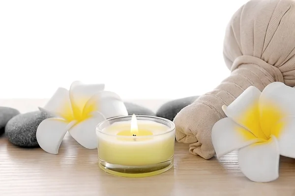 Massagebeutel mit Federkleid und Kerze, isoliert auf weiß — Stockfoto