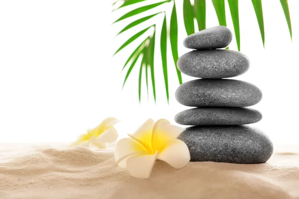 Few spa stones with plumeria on sand, isolated on white — Stock Photo, Image