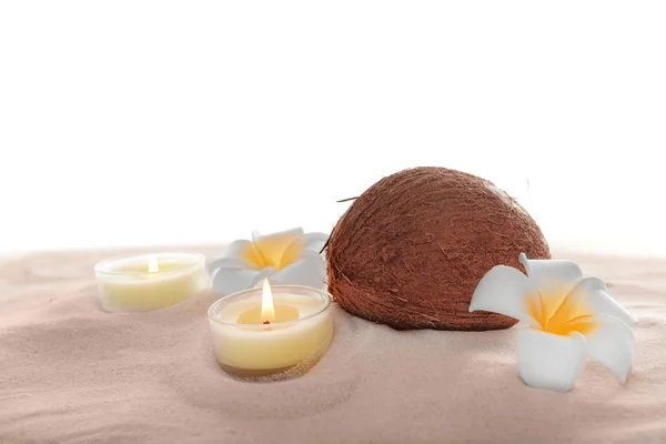 Coconut with plumeria and candles on sand, isolated on white — Stock Photo, Image