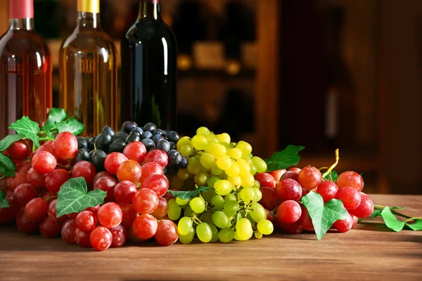 Grape and bottles with wine on a table — Stock Photo, Image