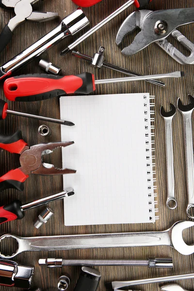 Different kinds of tools with a notebook on wooden background, closeup Royalty Free Stock Photos