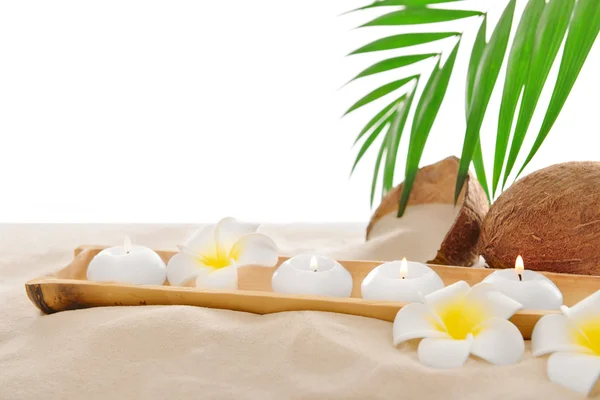 Coconut with candles and plumeria on sand, isolated on white Stock Photo