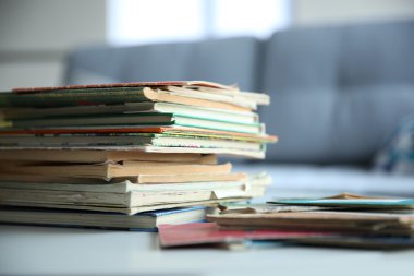 Eski kitaplar odada beyaz masa üzerinde kazık. Kitaplar ve arka plan bulanık odaklanmak