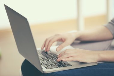 Kanepede dizüstü bilgisayarlı bir kadın oturuyor. 
