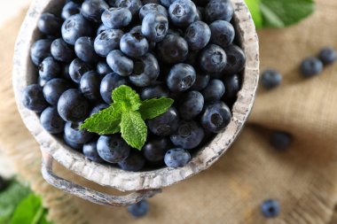 Lezzetli olgun yaban mersini masada kova yeşil yaprakları ile yakın çekim